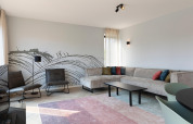 Modern living room at Resort Nieuwvliet-Bad 13 in the Netherlands with sectional sofa and abstract mural.