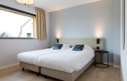 Modern twin bedroom with clean white bedding and light wood floors at Resort Nieuwvliet-Bad 13 in the Netherlands.