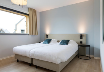 Modern twin bedroom with clean white bedding and light wood floors at Resort Nieuwvliet-Bad 13 in the Netherlands.