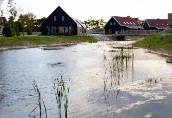 Resort Nieuwvliet-Bad 13 in the Netherlands with lodges, water, and greenery surrounding the area.