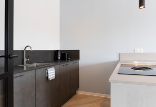Cucina moderna al Resort Nieuwvliet-Bad 13, Paesi Bassi, con lavello, piano a induzione e piano nero.
