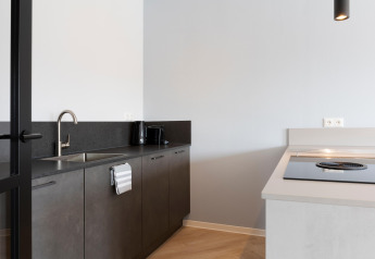 Modern kitchen at Resort Nieuwvliet-Bad 13, Netherlands, featuring black countertop, sink, and stove.