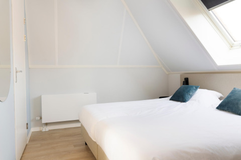 Camera luminosa al Resort Nieuwvliet-Bad 13 nei Paesi Bassi, con letto matrimoniale e lucernario inclinato.
