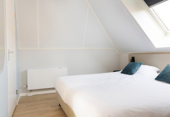 Bright bedroom at Resort Nieuwvliet-Bad 13 in the Netherlands, featuring a double bed and slanted skylight.