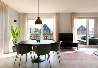 Bright, modern living and dining area at Resort Nieuwvliet-Bad 13, with large windows and stylish furnishings.