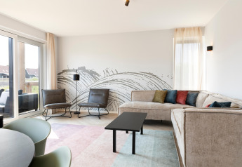 Bright living room with modern decor, a cozy sectional sofa, colorful cushions, and artistic wall mural at the lodge.