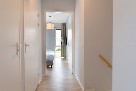 Corridoio luminoso al Resort Nieuwvliet-Bad 13 nei Paesi Bassi che conduce a una camera da letto moderna.