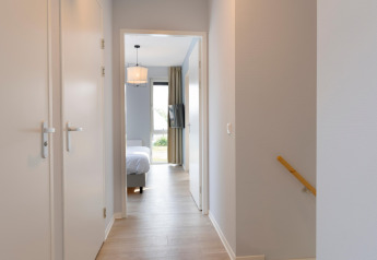 Bright hallway at Resort Nieuwvliet-Bad 13 in the Netherlands, leading to a bedroom with modern décor.