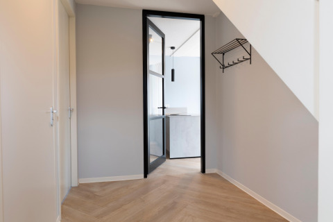 Ingresso del Resort Nieuwvliet-Bad 13 con porta in vetro, pavimento in legno e attaccapanni a muro nei Paesi Bassi.