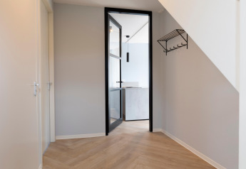 Entrance of Resort Nieuwvliet-Bad 13 featuring glass door, wooden floor and wall rack, located in the Netherlands.