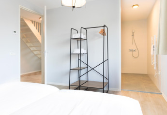 Modern bedroom with open clothes rack and walk-in shower at Resort Nieuwvliet-Bad 13, Netherlands.