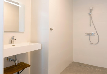 Modern minimalist bathroom with a walk-in shower and sink at Resort Nieuwvliet-Bad 13 in the Netherlands.