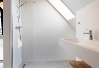 Modern bathroom at Resort Nieuwvliet-Bad 13 in the Netherlands with sloped ceiling, shower, and sink.