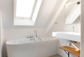 Bagno moderno al Resort Nieuwvliet-Bad 13 nei Paesi Bassi con vasca da bagno, lavandino e lucernario.