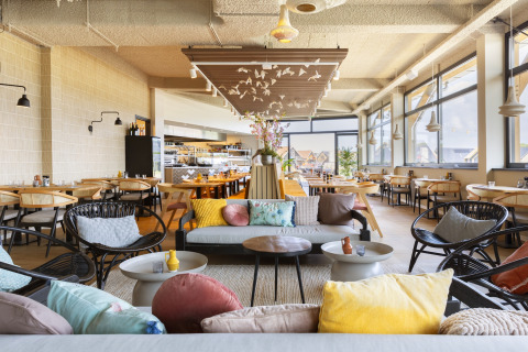 Ristorante luminoso e moderno al Resort Nieuwvliet-Bad 13 nei Paesi Bassi con divani e cuscini colorati.