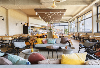 Ristorante luminoso e moderno al Resort Nieuwvliet-Bad 13 nei Paesi Bassi con divani e cuscini colorati.