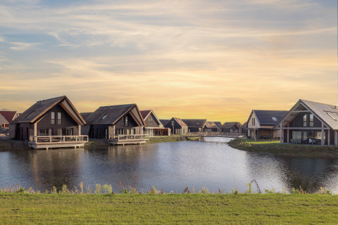 Moderni lodge sul lago al Resort Nieuwvliet-Bad 13 nei Paesi Bassi, con tramonto sullo sfondo.