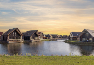 Moderni lodge sul lago al Resort Nieuwvliet-Bad 13 nei Paesi Bassi, con tramonto sullo sfondo.