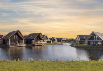 Modern lakeside lodges at Resort Nieuwvliet-Bad 13 in the Netherlands, with a beautiful sunset sky.