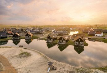 Sunrise at Resort Nieuwvliet-Bad 13 in the Netherlands, with modern waterfront lodges in a serene village.