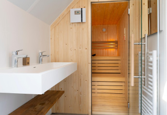 Modern sauna and bathroom at Resort Nieuwvliet-Bad 13 in the Netherlands with double sinks and glass door.