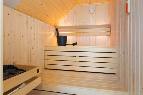 Vista interna di una sauna moderna in legno con panche, secchio e mestolo al Resort Nieuwvliet-Bad 13, Paesi Bassi.