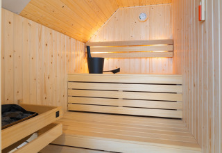 Vista interna di una sauna moderna in legno con panche, secchio e mestolo al Resort Nieuwvliet-Bad 13, Paesi Bassi.