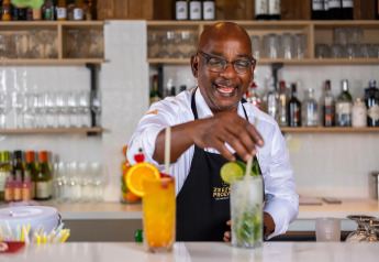 Bartender at Resort Nieuwvliet-Bad 13 in the Netherlands, smiling while preparing cocktails behind the bar.