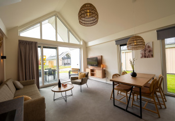 Moderne opholdsstue med højt til loftet og store vinduer i en lodge på Holiday Park Zeebad 14, Holland.