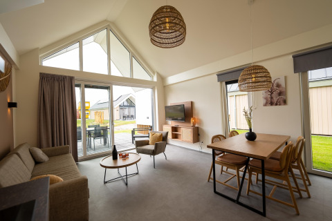 Modern living space with large windows and cozy decor at Holiday Park Zeebad 14 lodge in the Netherlands.
