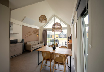 Modern living and dining area at Holiday Park Zeebad 14 lodge in the Netherlands with ample natural light.