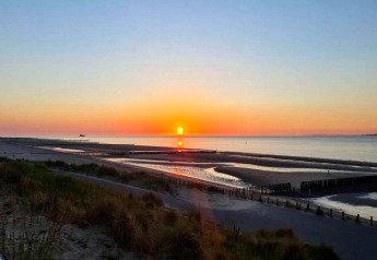 Solnedgang over stranden og havet set fra Holiday Park Zeebad 14 i Holland med fredeligt landskab.