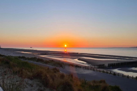 Solnedgang over stranden og havet set fra Holiday Park Zeebad 14 i Holland med fredeligt landskab.