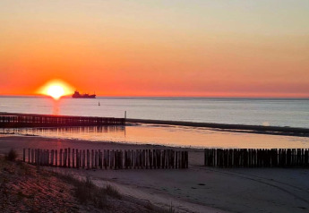 Sunset over the sea from Holiday Park Zeebad 14 in the Netherlands, with a ship on the horizon.