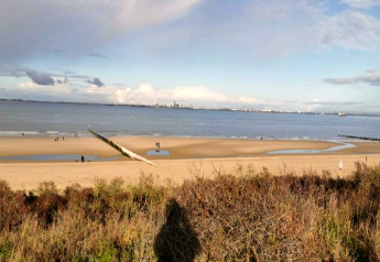 Udsigt over stranden og havet fra Holiday Park Zeebad 14 i Nederlandene med folk, sand og hav.