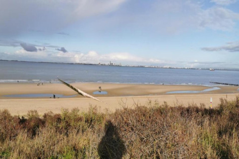 Beach and sea view from Holiday Park Zeebad 14 in the Netherlands, with people walking on the sand.