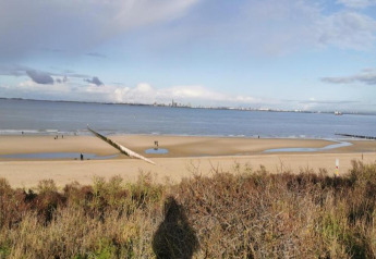 Beach and sea view from Holiday Park Zeebad 14 in the Netherlands, with people walking on the sand.