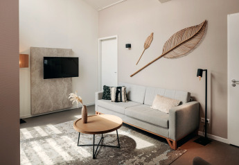 Moderne stue i Holiday Park Zeebad 11, Nederlandene, med lys sofa, TV og dekorative vægpynt.