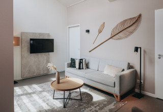 Soggiorno moderno all’Holiday Park Zeebad 11, Paesi Bassi, con divano, TV e decorazioni da parete.