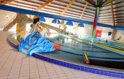 Indendørs swimmingpool på et lodge med børnevenlige figurer, rutschebane og farverig dekoration.