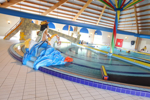 Indendørs swimmingpool på et lodge med børnevenlige figurer, rutschebane og farverig dekoration.