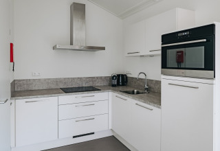 Modern kitchen in Holiday Park Zeebad 11, Netherlands, with white cabinets, appliances, and a sleek design.