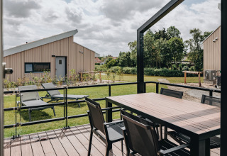 Terrasse mit Esstisch und Liegestühlen im Holiday Park Zeebad 11, Niederlande, moderne Hütte und Garten.