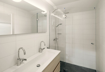 Modern bathroom with double sink, walk-in shower and large mirror at Holiday Park Zeebad 11, Netherlands.
