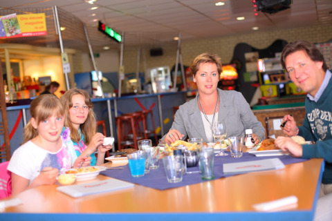 Una familia sentada en una mesa en una cabaña disfruta de una comida juntos en un ambiente agradable.