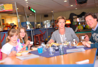 Una familia sentada en una mesa en una cabaña disfruta de una comida juntos en un ambiente agradable.
