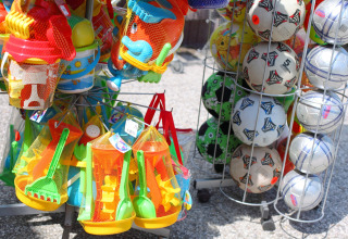 Exhibición al aire libre de juguetes de playa y balones de fútbol para niños junto a una cabaña.