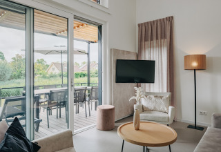Modern living room at Holiday Park Zeebad 12 in the Netherlands with terrace and outdoor dining area view.