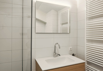 Moderne badeværelse med hvid vask, spejl, vandhane og radiator på Holiday Park Zeebad 12 i Nederlandene.