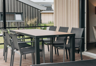 Zona pranzo esterna sulla terrazza della lodge Holiday Park Zeebad 12 nei Paesi Bassi, con sedie moderne.